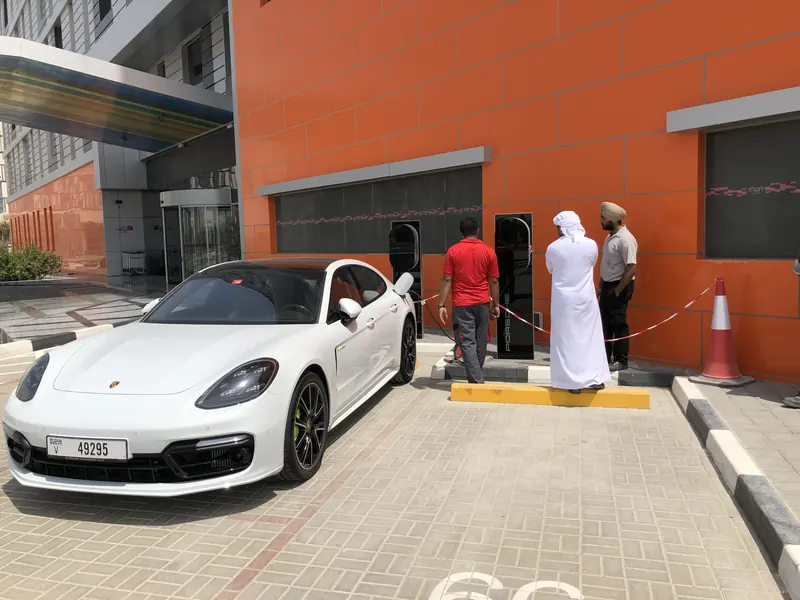 EV charging bay at Aloft Hotel with a white Porsche plugged in and charger units against an orange façade