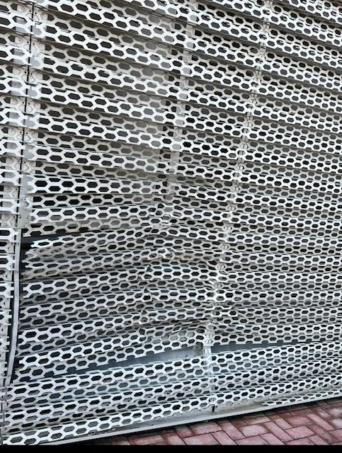 Close-up of damaged honeycomb-perforated façade cladding panel at an Audi showroom