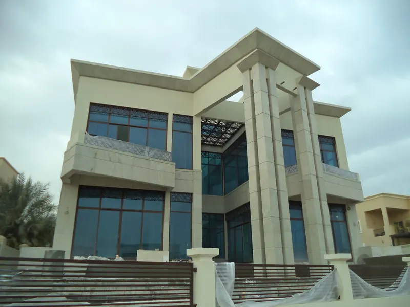 Rear elevation of a luxury Emirates Hills villa built by Al Jawadri Contracting with stone columns and floor-to-ceiling glazing