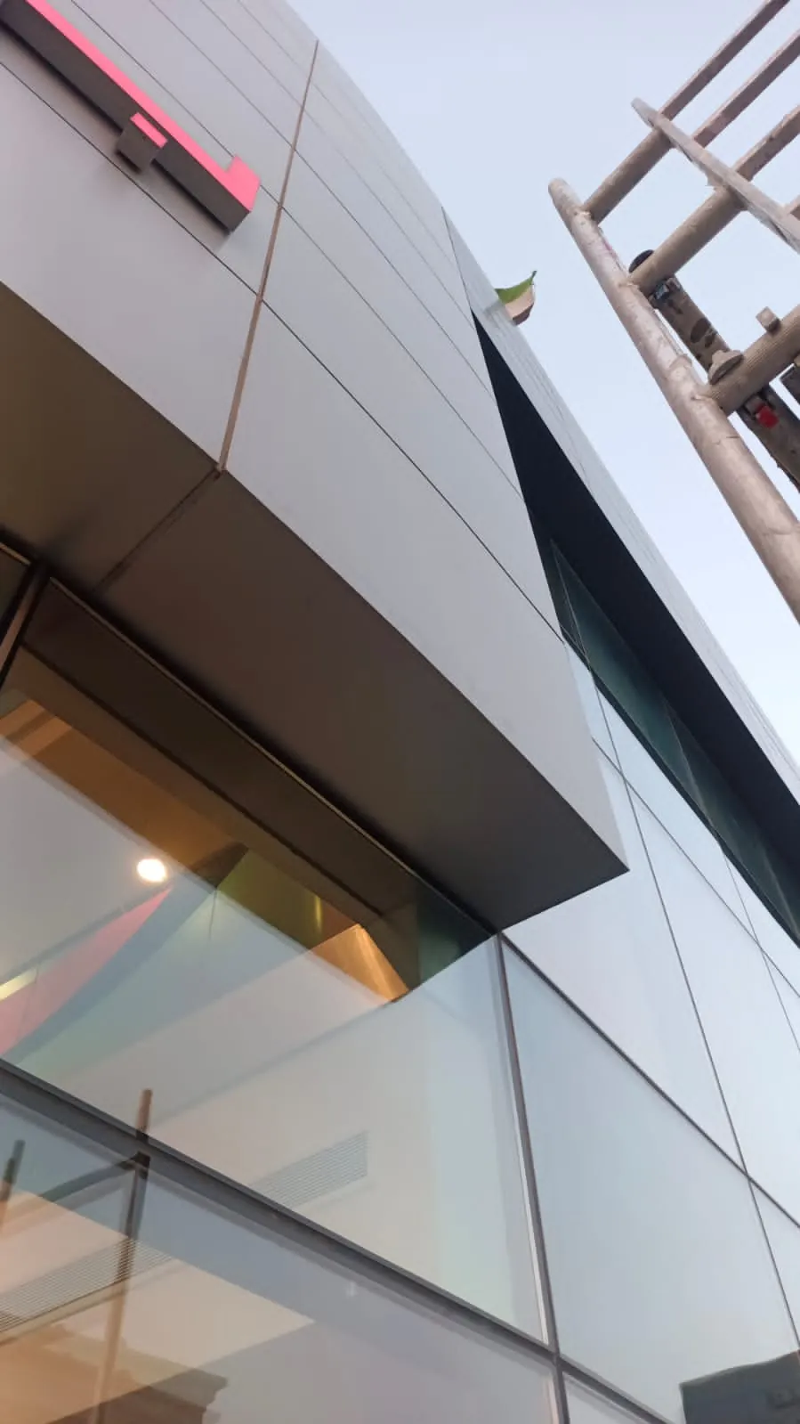 Porsche showroom cladding after rectification, aligned panels beside glazing and canopy